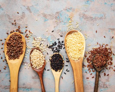 Beton zemin üzerinde çeşitli pirinç setleri: siyah, basmati, kahverengi ve kırmızı karışık pirinç