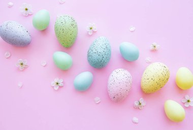 Pembe arka planda bahar çiçekleri olan renkli Paskalya yumurtaları. Renkli Yumurta Tatil Kenarı.
