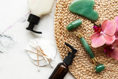 Beyaz mermer arka planda kozmetik ürünü ile yüz masajı yeşim silindiri