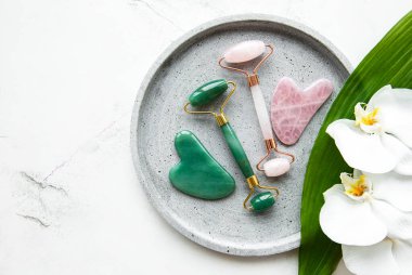 Güzellik masajı için yeşim yüz silindirleri. Düz beyaz mermer zemin üzerinde yatıyordu