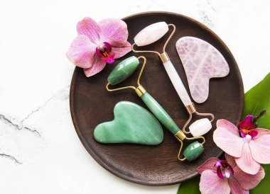 Güzellik masajı için yeşim yüz silindirleri. Düz beyaz mermer zemin üzerinde yatıyordu