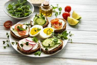 Sağlıklı sebzeli sandviçler ve ahşap bir masada mikro yeşiller.
