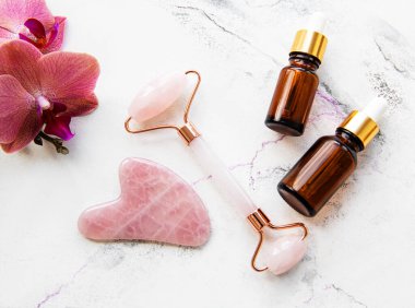 Beyaz mermer arka planda kozmetik ürünü ile yüz masajı yeşim silindiri