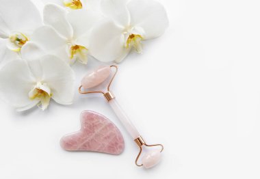 Yüz masajı yeşim taşları ve beyaz arka planda orkide çiçekleri