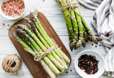 Bir sürü çiğ kuşkonmaz, ahşap zemin üzerinde farklı baharat ve malzemeler barındırır. Üst manzara, düz uzanma.
