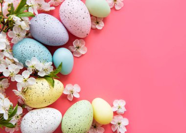 Pembe arka planda bahar çiçekleri olan renkli Paskalya yumurtaları. Renkli Yumurta Tatil Kenarı.
