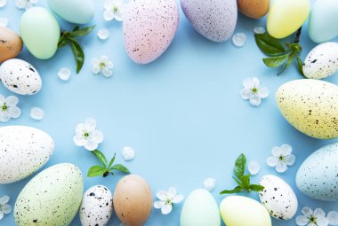 Mavi arka planda bahar çiçekleri olan renkli Paskalya yumurtaları. Renkli Yumurta Tatil Kenarı.