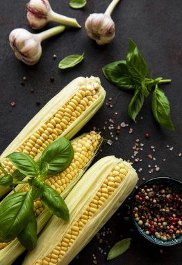 Siyah arka planda olgun mısır koçanı ve baharatlar.