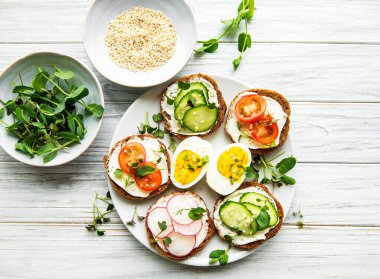 Sağlıklı sebzeli sandviçler ve ahşap bir masada mikro yeşiller.