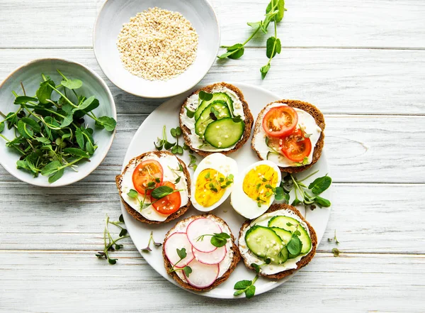 Sağlıklı sebzeli sandviçler ve ahşap bir masada mikro yeşiller.
