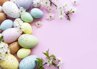 Pembe arka planda bahar çiçekleri olan renkli Paskalya yumurtaları. Renkli Yumurta Tatil Kenarı.