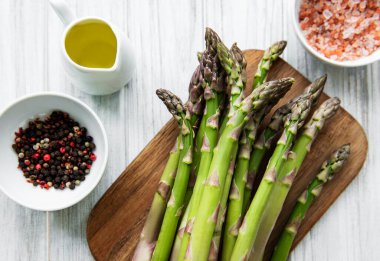 Bir sürü çiğ kuşkonmaz, ahşap zemin üzerinde farklı baharat ve malzemeler barındırır. Üst manzara, düz uzanma.