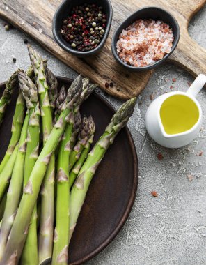 Bir sürü çiğ kuşkonmaz, gri beton arka planda farklı baharat ve malzemelerle yapılır. Üst manzara, düz uzanma.