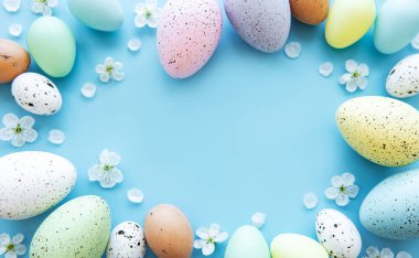 Mavi arka planda bahar çiçekleri olan renkli Paskalya yumurtaları. Renkli Yumurta Tatil Kenarı.