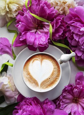 Beyaz mermer arka planda pembe şakayık ve bir fincan kahve. Çiçek arkaplan. Üst görünüm