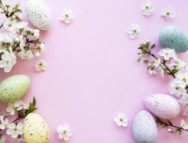 Pembe arka planda bahar çiçekleri olan renkli Paskalya yumurtaları. Renkli Yumurta Tatil Kenarı.