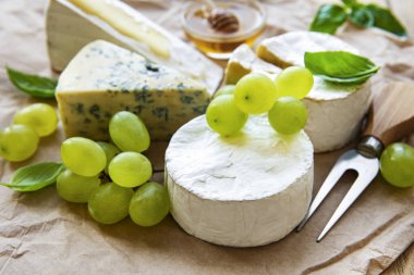 Masada çeşitli peynir, fesleğen ve üzümler var.