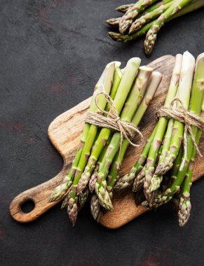 Siyah beton arka planda taze yeşil kuşkonmaz. Düz yatıyordu