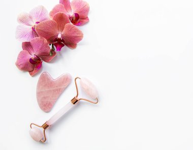 Yüz masajı yeşim taşları ve beyaz arka planda orkide çiçekleri