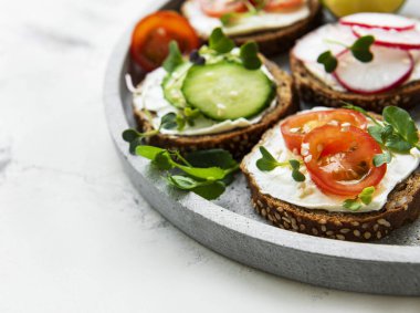 Sağlıklı sebzeli sandviçler ve beyaz arka planda mikro yeşiller.