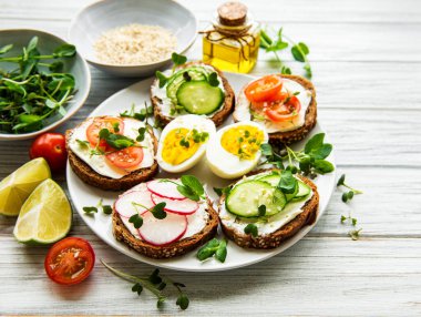 Sağlıklı sebzeli sandviçler ve ahşap bir masada mikro yeşiller.