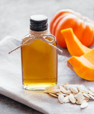 Gri beton arka planda balkabağı tohumu yağıyla dolu şişe.