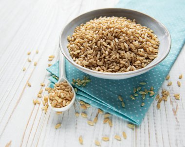 Beyaz ahşap zemin üzerinde çiğ kahverengi pirinç