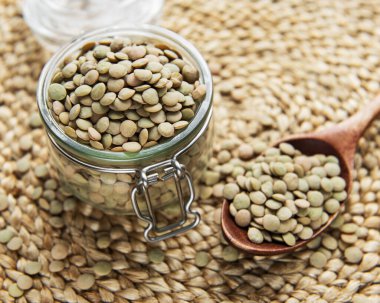 Masadaki cam kavanozdaki çiğ mercimek yığını.