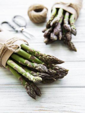 Taze yeşil kuşkonmaz, makas ve eski ahşap masanın üzerinde iplik. Düz yatıyordu