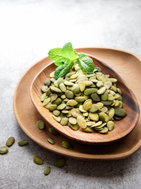 Gri beton arka planda kabak tohumlu ahşap bir tabak.