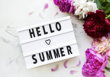 İçinde Hello Summer yazlığı ve şakayık çiçekleri olan ışıklı kutu mermer arka planda