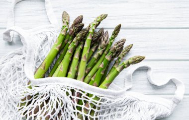 Kuşkonmaz, eski ahşap bir arka planda bir eko-ağ torbasında bulunur.