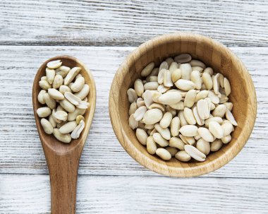 Ahşap arka planda ahşap bir kasede soyulmuş fıstıklar.