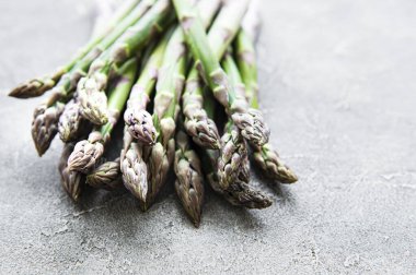 Gri beton arka planda taze yeşil kuşkonmaz. Düz yatıyordu