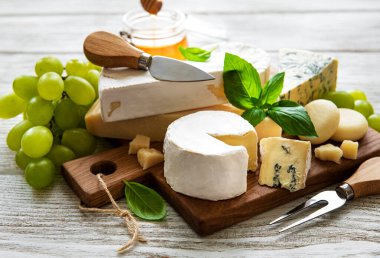 Beyaz ahşap arka planda çeşitli peynir çeşitleri