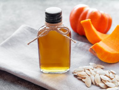 Gri beton arka planda balkabağı tohumu yağıyla dolu şişe.