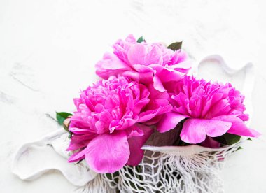 Güzel pembe şakayıklar beyaz mermer arka planda şık bir iplik torbasında. Çiçek doğal arka plan.