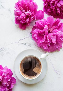 Beyaz arka planda pembe şakayık ve bir fincan kahve. Çiçek arkaplan. Üst görünüm.