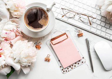 Düz manzaralı kadınlar bürosu masasında çiçeklerle yatıyordu. Dizüstü bilgisayarlı, çiçekli şakayıklı, aksesuarlı, defterli, gözlüklü, beyaz arka planda bir fincan kahveli bir kadın çalışma alanı. Tatil arkaplanı. Boşluğu kopyala