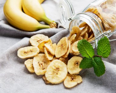 Kurutulmuş muz dilimleri ya da gri beton arka planda cips.