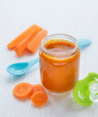 Cam kavanozda kaşıkla ezilmiş bebek havucu, bebek maması.