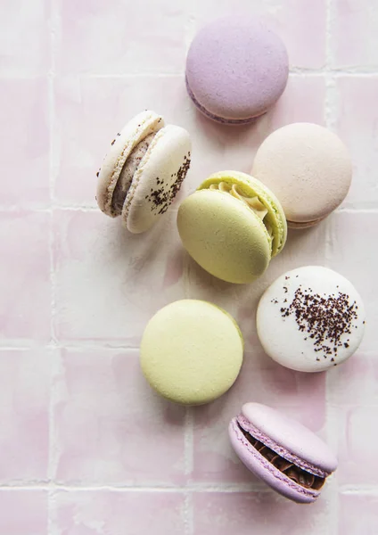 Colorful french macaroons on pink tile background