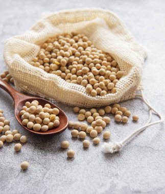 Beton arka planda soya fasulyesi dolu bir çevre torbası.