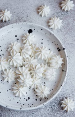 Seramik kasede beton zemin üzerinde küçük beyaz kremalar.