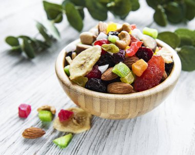 Beyaz ahşap arka planda çeşitli kurutulmuş meyveler ve fındıklar..