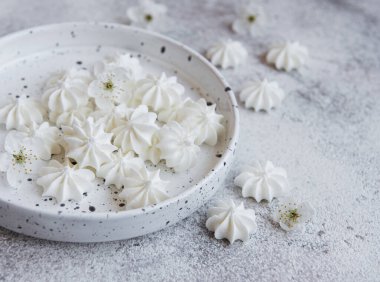 Seramik kasede beton zemin üzerinde küçük beyaz kremalar.