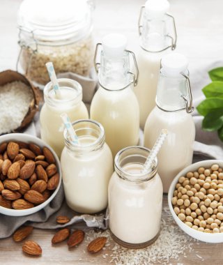 Beton arka planda cam şişelerde alternatif vejetaryen süt türleri. Üst görünüm