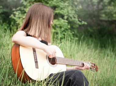 Parkta gitar çalan genç kız.