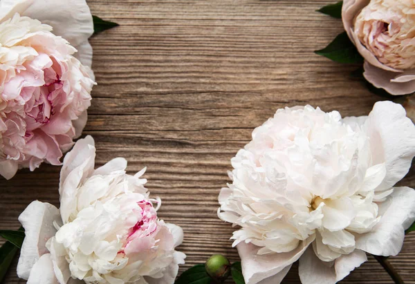Pink peony flowers as a border on a old wooden background