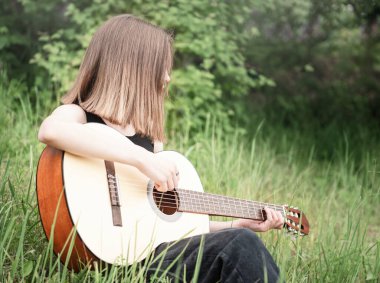 Parkta gitar çalan genç kız.